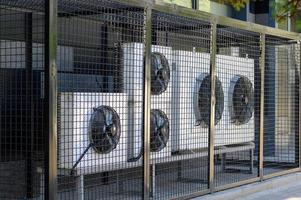 Air conditioning compressor system on a modern building protected by a metal fence. photo