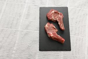Raw cowboy steak and spices on a black wooden background. photo