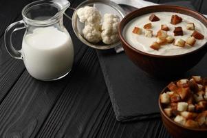 Cream of cauliflower soup on a dark wooden background. photo