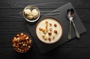 Cream of cauliflower soup on a dark wooden background. photo