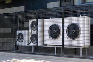 sistema de compresor de aire acondicionado en un edificio moderno protegido por una valla metálica. foto