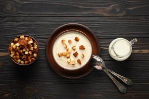Cream of cauliflower soup on a dark wooden background. photo