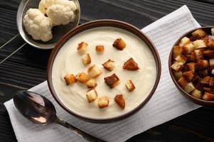 Cream of cauliflower soup on a dark wooden background. photo