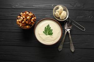 Cream of cauliflower soup on a dark wooden background. photo