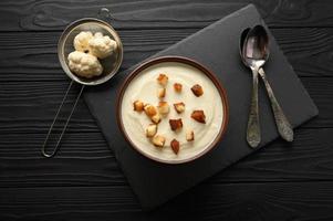 Cream of cauliflower soup on a dark wooden background. photo