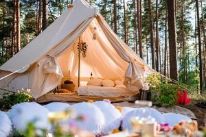 Picnic in the nature, table, carpets, wigwam, tent, pillows in the park. photo