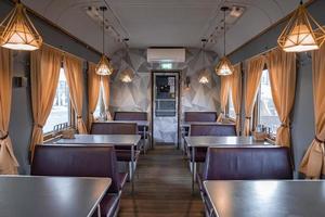 Seats and tables arranged in illuminated train coach at famous Peatus in town photo