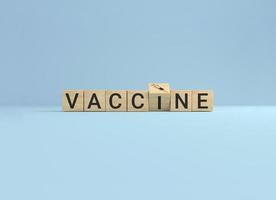 Wooden cube block flip over word vaccine to syringe icon on blue studio background. photo