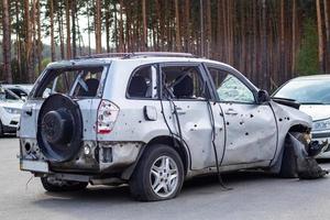 Shot, damaged cars during the war in Ukraine. The vehicle of civilians affected by the hands of the Russian military. Shrapnel and bullet holes in the body of the car. Ukraine, Irpen - May 12, 2022. photo