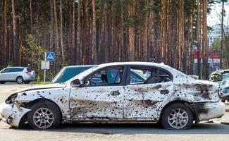 Shot, damaged cars during the war in Ukraine. The vehicle of civilians affected by the hands of the Russian military. Shrapnel and bullet holes in the body of the car. Ukraine, Irpen - May 12, 2022. photo