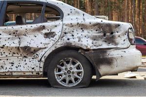 tiro, coches dañados durante la guerra en ucrania. el vehículo de civiles afectados por las manos de los militares rusos. metralla y agujeros de bala en la carrocería del coche. ucrania, irpen - 12 de mayo de 2022. foto