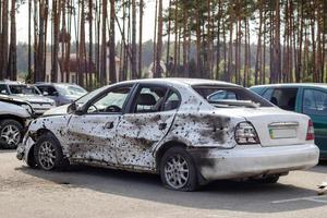 A car destroyed by shrapnel from a rocket that exploded nearby. Irpensky automobile cemetery. Consequences of the invasion of the Russian army in Ukraine. Ukraine, Irpen - May 12, 2022. photo