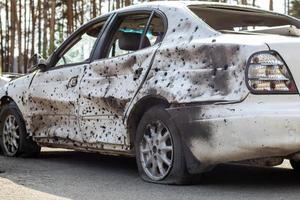 tiro, coches dañados durante la guerra en ucrania. el vehículo de civiles afectados por las manos de los militares rusos. metralla y agujeros de bala en la carrocería del coche. ucrania, irpen - 12 de mayo de 2022. foto