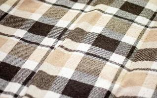 Blanket. Texture of checkered wool fabric in brown color. Checkered texture. Warm brown alpaca wool or cashmere blanket. Beige, brown square shaped wool fabric for home design. photo
