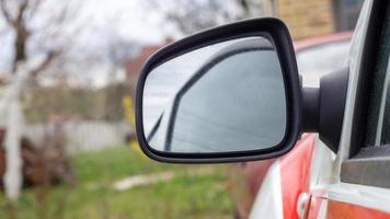 Side left black plastic rearview mirror on a white car. Exterior side-view mirror on the driver's side, electrically adjustable and heated. photo