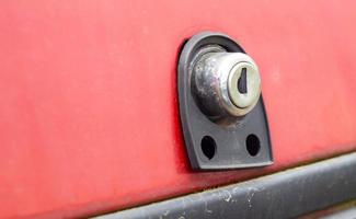 Old car trunk lock. Trunk lock details. Close-up of a handle to open the back door of a vintage red car. photo
