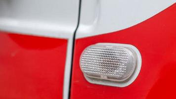 Automotive light bulb. Turn signal on the side of the car. A white turn signal on a red crossover, which is located on the side on the right side of the fender surface. photo