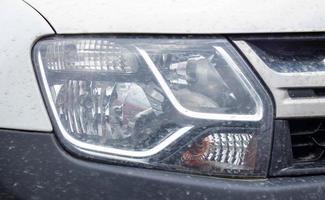 Front right headlight for Renault Duster. Crossover or SUV in white with a black bumper. View of the front of the car. Detailed close-up light on a car. Exterior detail. Ukraine, Kyiv - June 12. 2022. photo