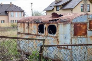 una choza de metal podrida y oxidada en ruinas en un lugar de trabajo. un viejo remolque de construcción de estaño con techo redondo y una ventana rota de un prado o pasto con una barra de remolque. foto