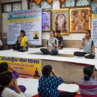 New Delhi, India, June 19 2022 -Group Yoga exercise session for people of different age groups in Balaji Temple, Vivek Vihar, International Yoga Day, Big group of adults attending yoga class in temple photo