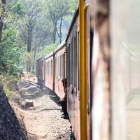 Toy Train moving on mountain slopes, beautiful view, one side mountain, one side valley moving on railway to the hill, among green natural forest. Toy train from Kalka to Shimla in India photo