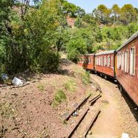 Toy Train moving on mountain slopes, beautiful view, one side mountain, one side valley moving on railway to the hill, among green natural forest. Toy train from Kalka to Shimla in India photo