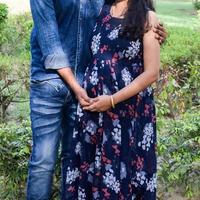 Indian couple posing for maternity baby shoot. The couple is posing in a lawn with green grass and the woman is falunting her baby bump in Lodhi Garden in New Delhi, India photo