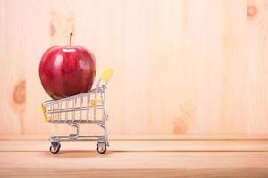 apple red on shopping cart with wood floor background photo