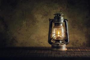 kerosene lamp oil lantern burning with glow soft light on aged wood floor photo