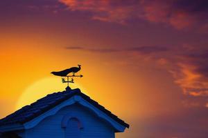 weather vane at sunrise with bright colors in clouds for early morning wake up photo