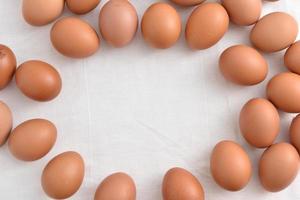 Fresh brown Eggs on white fabric background photo