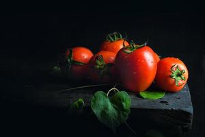 Tomato vegetable and green leaf on old dark wooden floor antique black photo