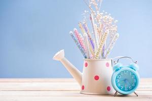 Pencil and pen in watering can have clock on wood vintage with office concept. photo