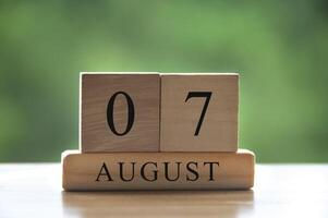 Texto de la fecha del calendario del 7 de agosto en bloques de madera con parque de fondo borroso. copie el espacio y el concepto de calendario foto