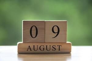 Texto de la fecha del calendario del 9 de agosto en bloques de madera con un parque de fondo borroso. copie el espacio y el concepto de calendario foto