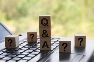 Q and A text on wooden block on top of laptop with blurred nature background. photo