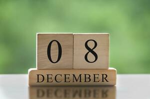 Texto del 8 de diciembre sobre bloques de madera con fondo de naturaleza borrosa. concepto de calendario foto