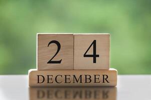 24 de diciembre texto sobre bloques de madera con fondo de naturaleza borrosa. concepto de calendario foto