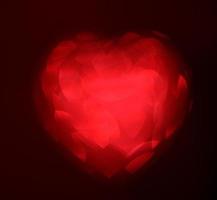 Desenfoque rojo en forma de corazón de luz bokeh sobre un fondo negro foto