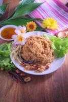 Fluffy spicy catfish with mango sauce Dish dishes on wooden floor Yum Pla-duke Fu photo