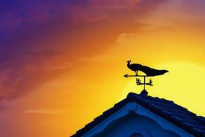weather vane at sunrise with bright colors in clouds for early morning wake up photo