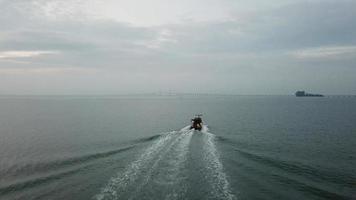 antenn följ baksidan av båten flytta mot penang bridge under haze day. video