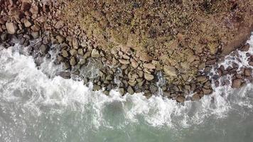 rotazione aerea guardare in basso grande onda splash ha colpito la roccia. video