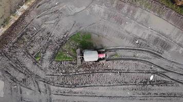 mirada aérea hacia abajo tractor arado cultivar el suelo en el campo de arroz. video