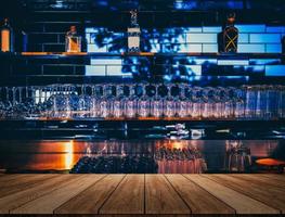 wooden table in front of abstract blurred restaurant lights background of bar photo