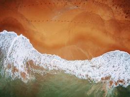 Beach on aerial drone top view with ocean waves reaching shore. photo