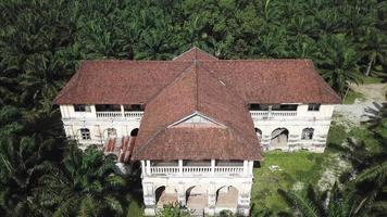 vue aérienne bâtiment colonial manoir de 99 portes dans un domaine de palmiers à huile envahi par la végétation. video