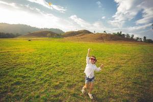 niña corriendo con cometa feliz y sonriente en el campo de verano foto