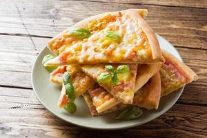 Pieces of homemade pizza on a plate on a wooden table. photo