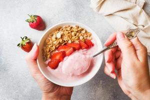 Homemade yogurt with fresh strawberries and muesli. The concept of a healthy Breakfast. Hands in shot. photo